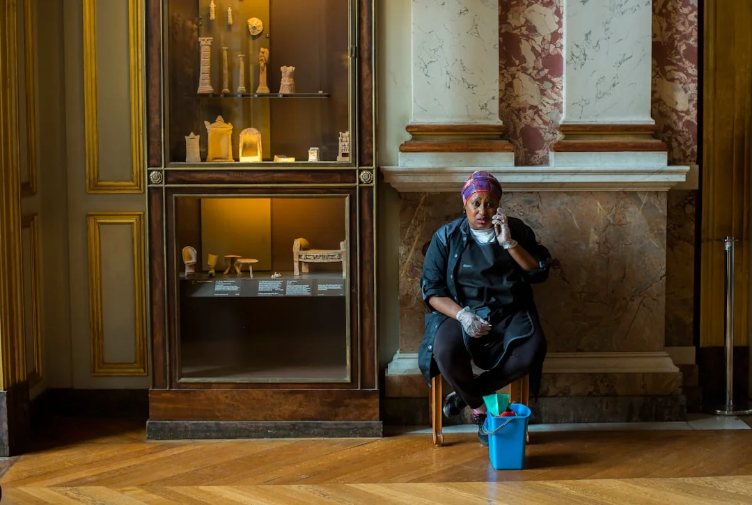 From above anonymous housekeeper in yellow rubber gloves spraying cleaner to chrome water faucet in bathroom